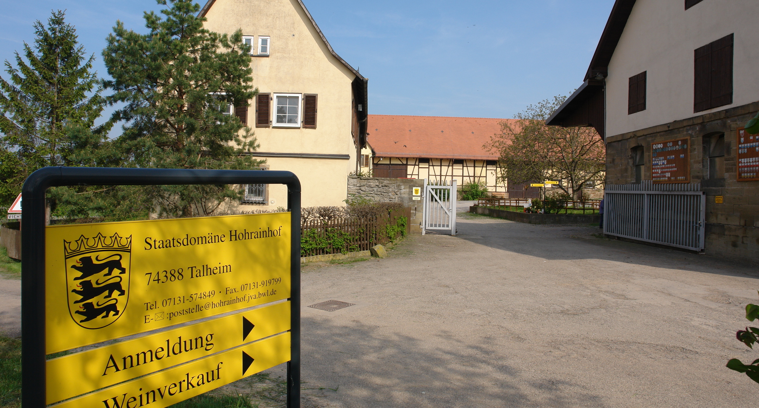 Blick in den Hof unserer Außenstelle, im Vordergrund ein gelbes Schild mit Adresse und Richtungspfeilen 