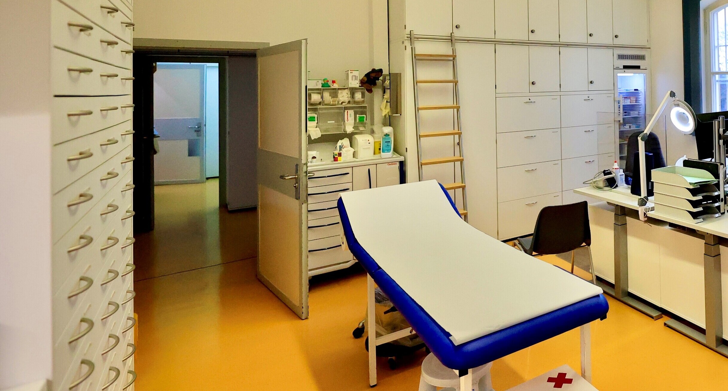 Blick in die Krankenabteilung mit Behandlungsliege und weißen Schränken